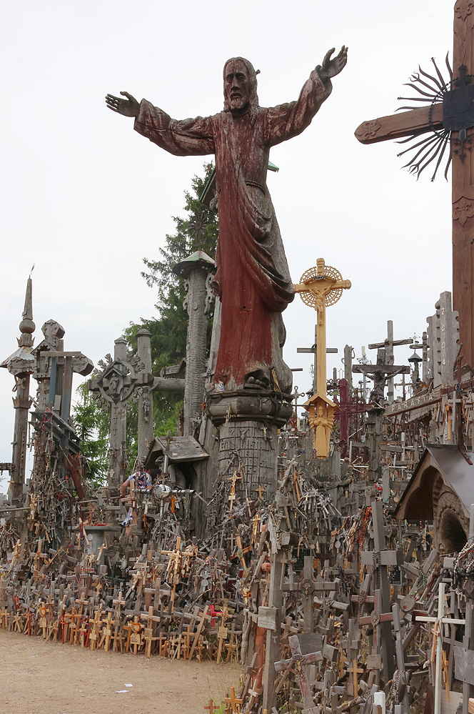 Eine Überlebensgroße Jesusfigur, die über hunderten Kreuzen ganz unterschiedlicher Größen steh, von 2-3 Metern bis runter auf wenige Zentimeter