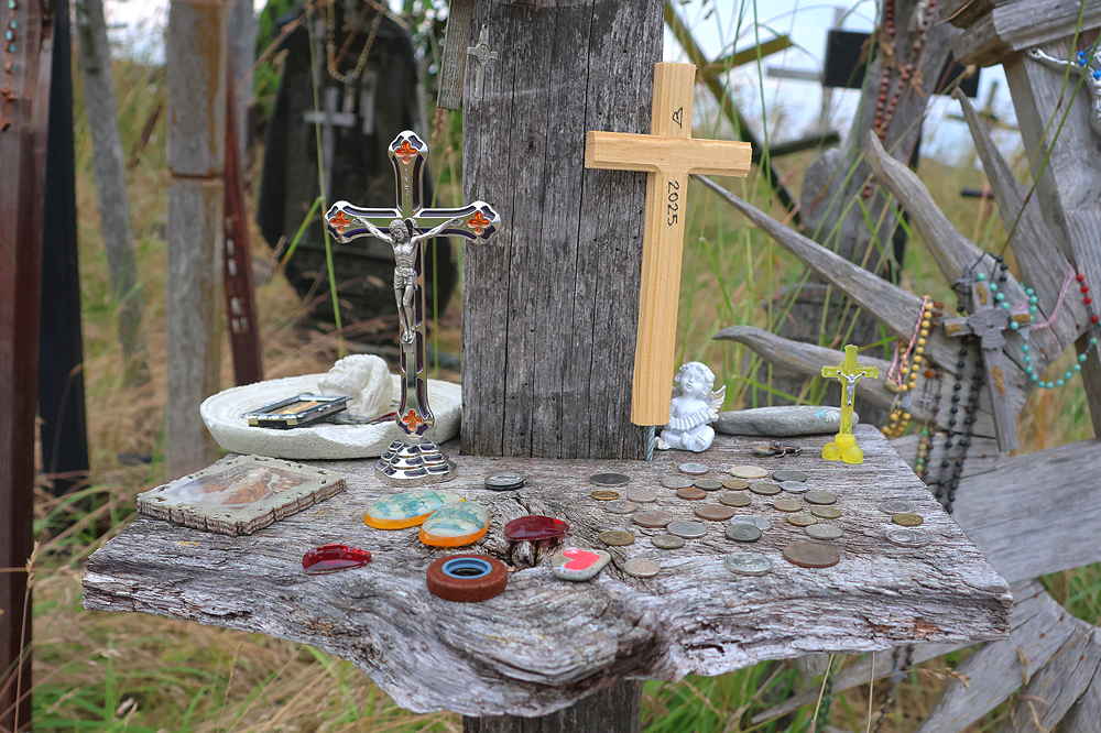 Kleines an einem Kreuz befestigtes steinernes Tablett mit Kreuzen, Engeln, Münzen und anderen persönlichen Erinnerungsstücken